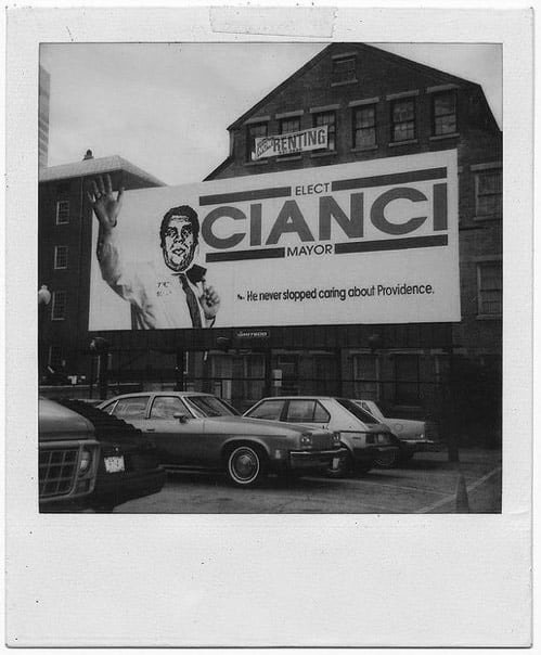 A black and white Polaroid photo of Shepard Fairey's infamous defacing of a Cianci campaign billboard in 1990. Some view the event as a catalyst for Cianci's reelection and Fairey's rise to prominence as guerilla 'street artist'
